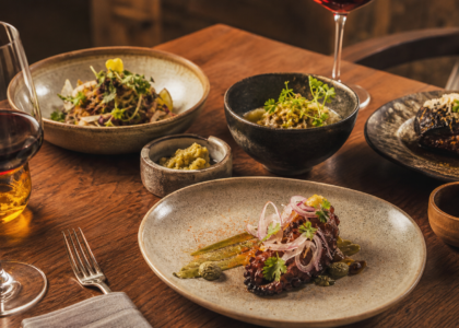 Platillos mexicanos contemporáneos y copas de vino en una mesa de experiencia gastronómica.