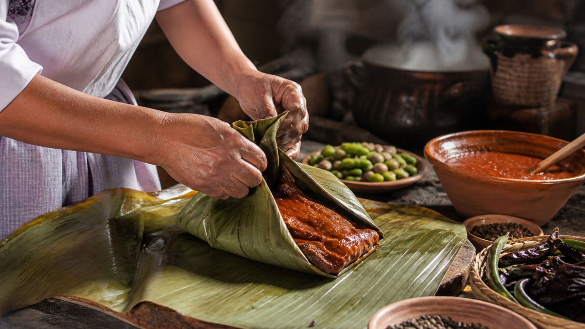 Mixiotes de Hidalgo recién cocidos al vapor junto a tortillas, salsas y manos de una cocinera tradicional