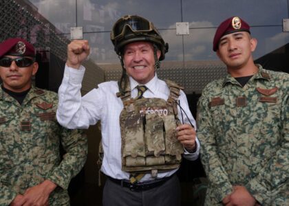 Ricardo Monreal porta chaleco y casco tácticos junto a dos militares durante una exhibición.